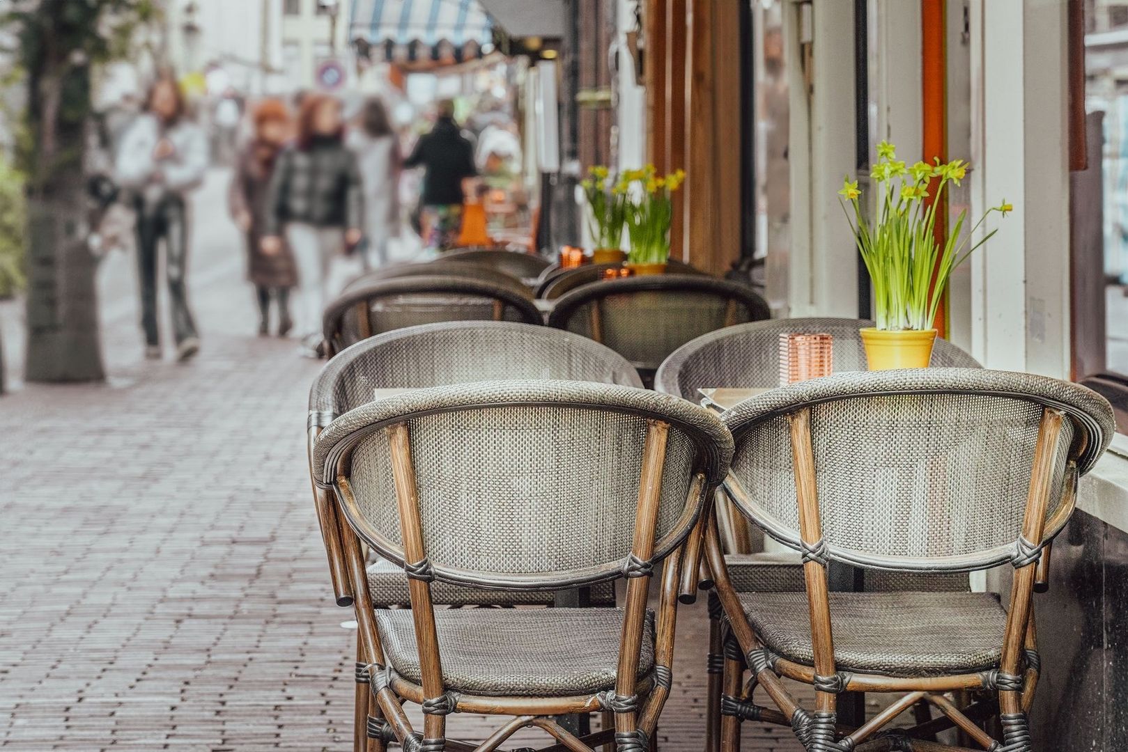 Outdoor café seating along a pedestrian street with potted flowers